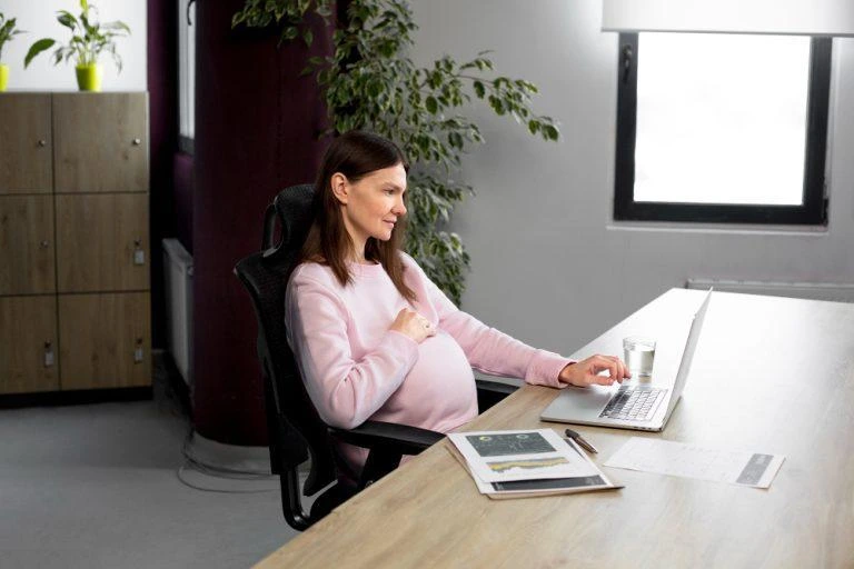 Salariată însărcinată lucrând la birou